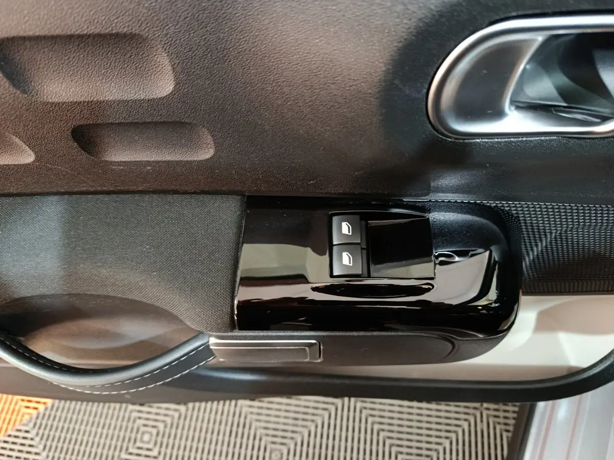 Gros plan sur les commandes de lève-vitres côté conducteur de la Citroën C3 gris foncé 2024 PureTech 83 BVM MAX.