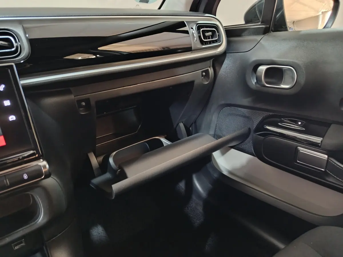 Intérieur de la Citroën C3 PureTech 83 BVM MAX 2024, vue côté passager sur la boîte à gants ouverte et tableau de bord noir.
