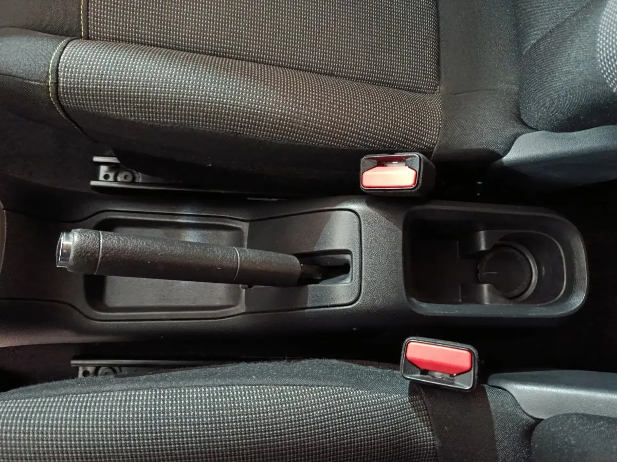 Vue plongeante sur la console centrale noire avec frein à main manuel et ceintures rouges de la Citroën C3 gris foncé 2024.