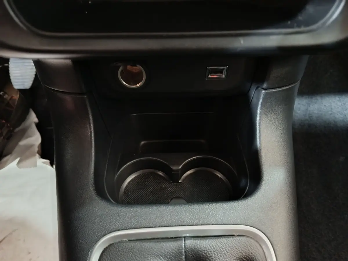 Gros plan sur la console centrale noire de la Citroën C3 2024 avec prises USB et allume-cigare visibles.