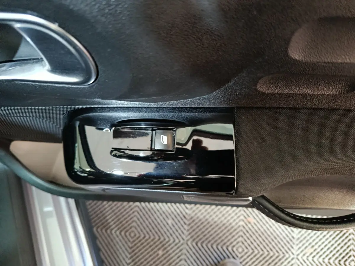 Commande de lève-vitre électrique côté conducteur sur panneau de porte intérieure d'une Citroën C3 gris foncé 2024.