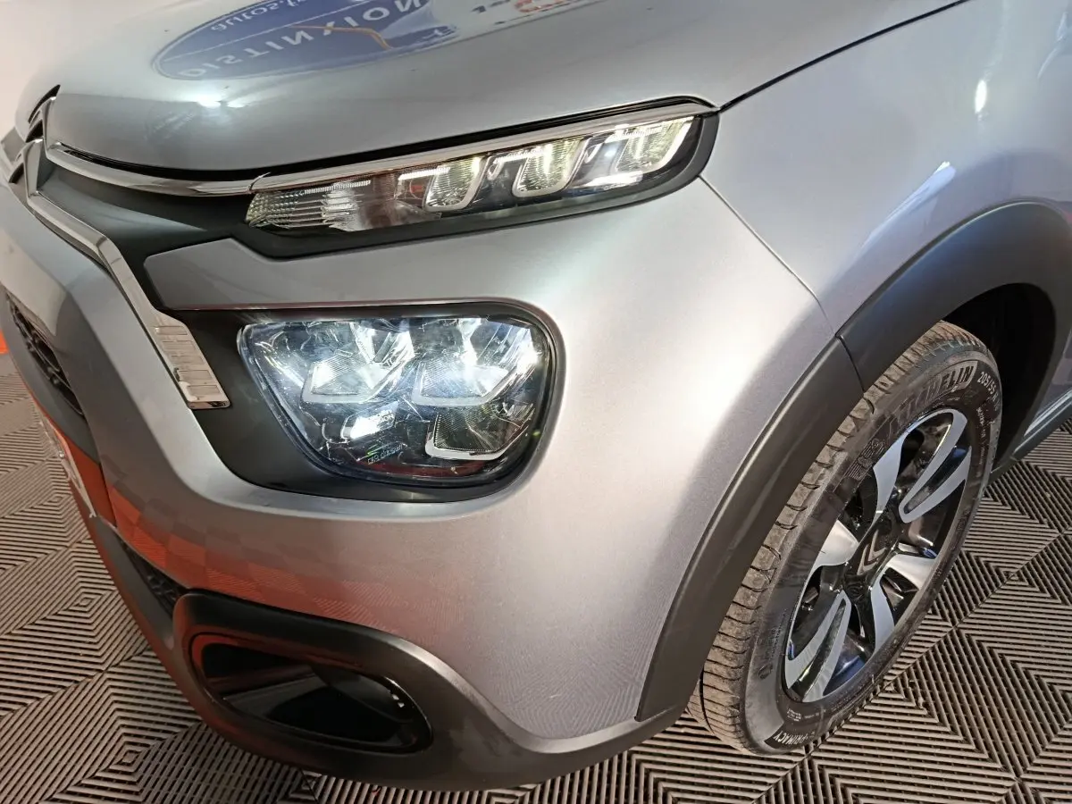 Gros plan sur l'avant droit gris foncé d'une Citroën C3 2024, mettant en valeur ses phares LED et sa roue.