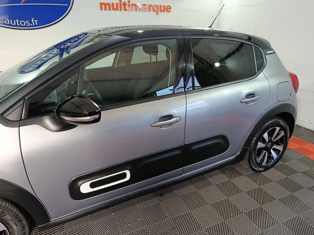 Profil côté gauche d'une Citroën C3 gris foncé 2024 avec protections latérales noires et jantes stylisées.