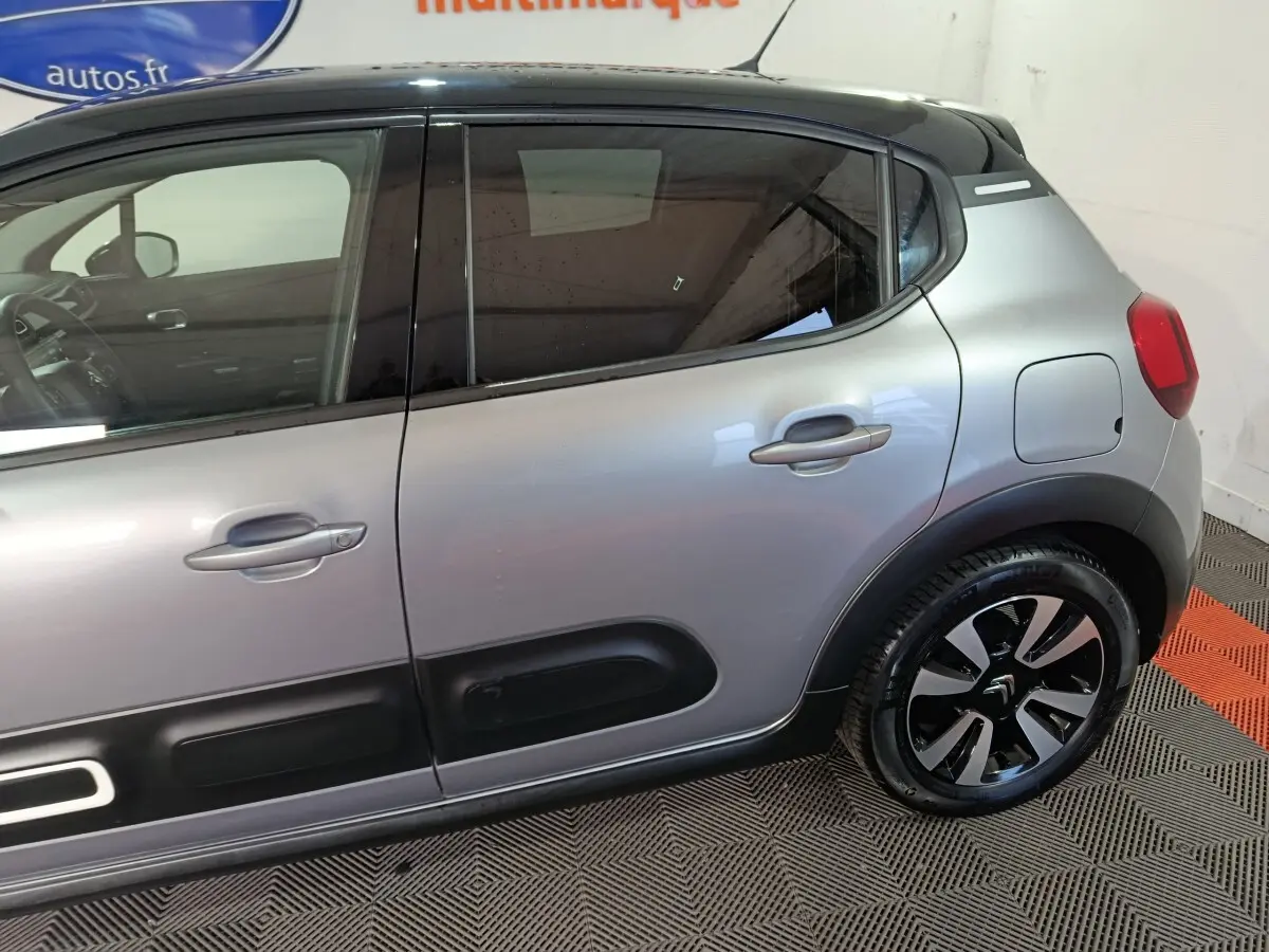 Vue latérale droite d'une Citroën C3 gris foncé avec protections de porte noires et jantes stylisées.