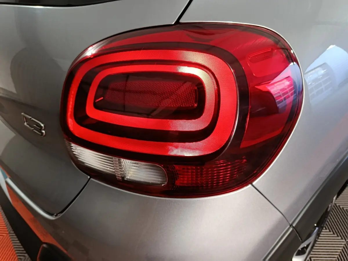 Gros plan sur le feu arrière droit rouge de la Citroën C3 gris foncé, avec logo C3 visible sur la carrosserie.