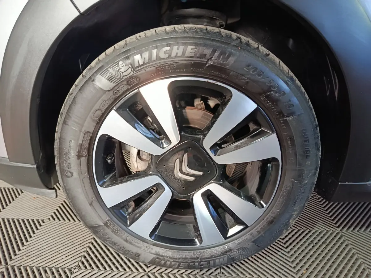 Gros plan sur la roue avant droite d'une Citroën C3 gris foncé, mettant en valeur la jante bicolore et le logo Citroën central.
