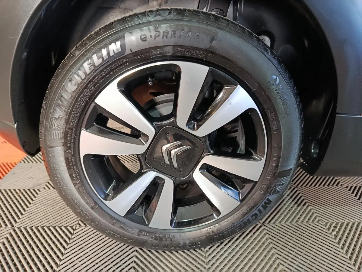 Gros plan sur la jante alliage bicolore avec logo Citroën, montée sur un pneu Michelin d'une C3 gris foncé 2024.