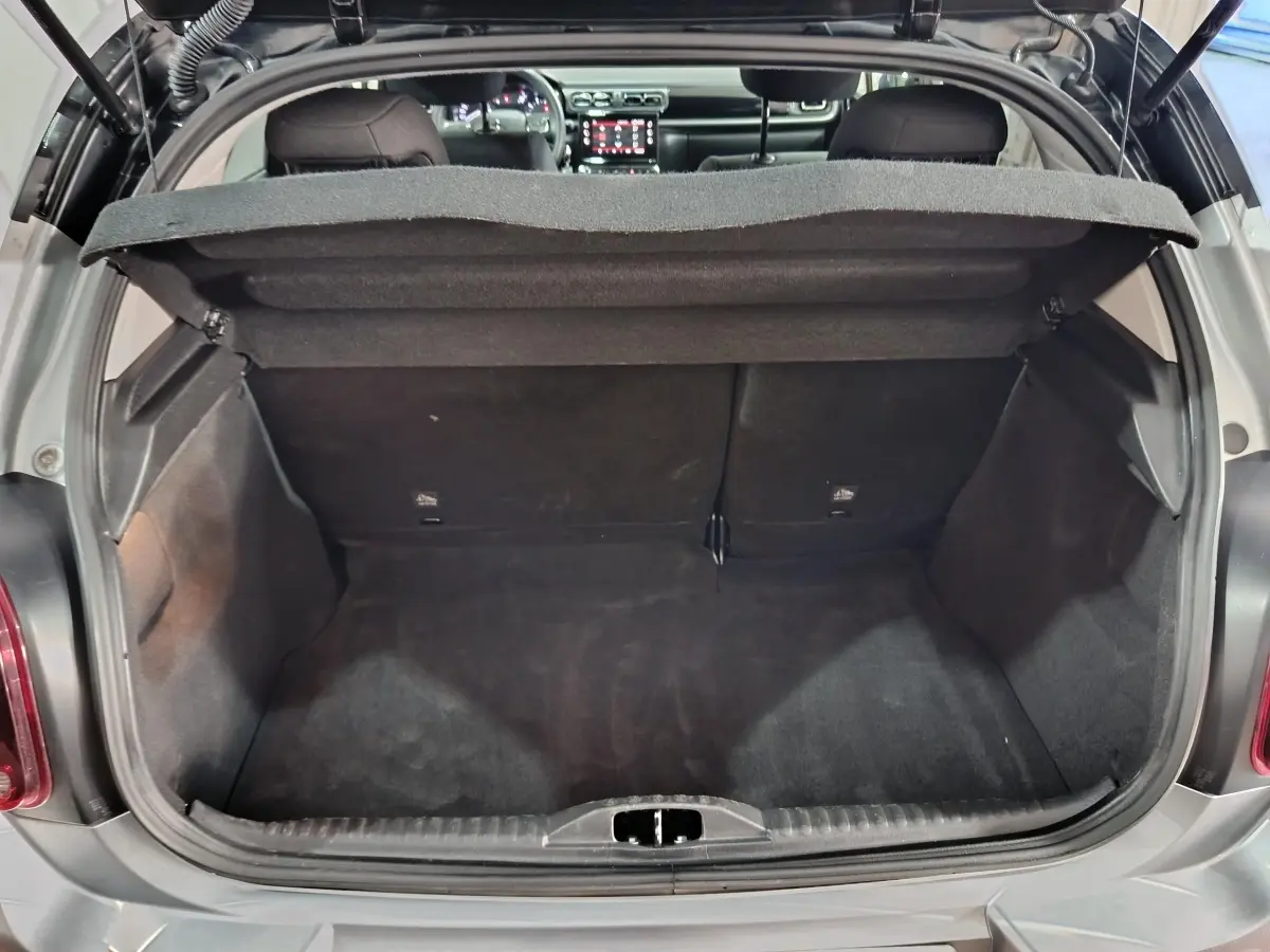 Coffre ouvert vu de l'arrière d'une Citroën C3 gris foncé, montrant l'espace de chargement et l'intérieur du véhicule.