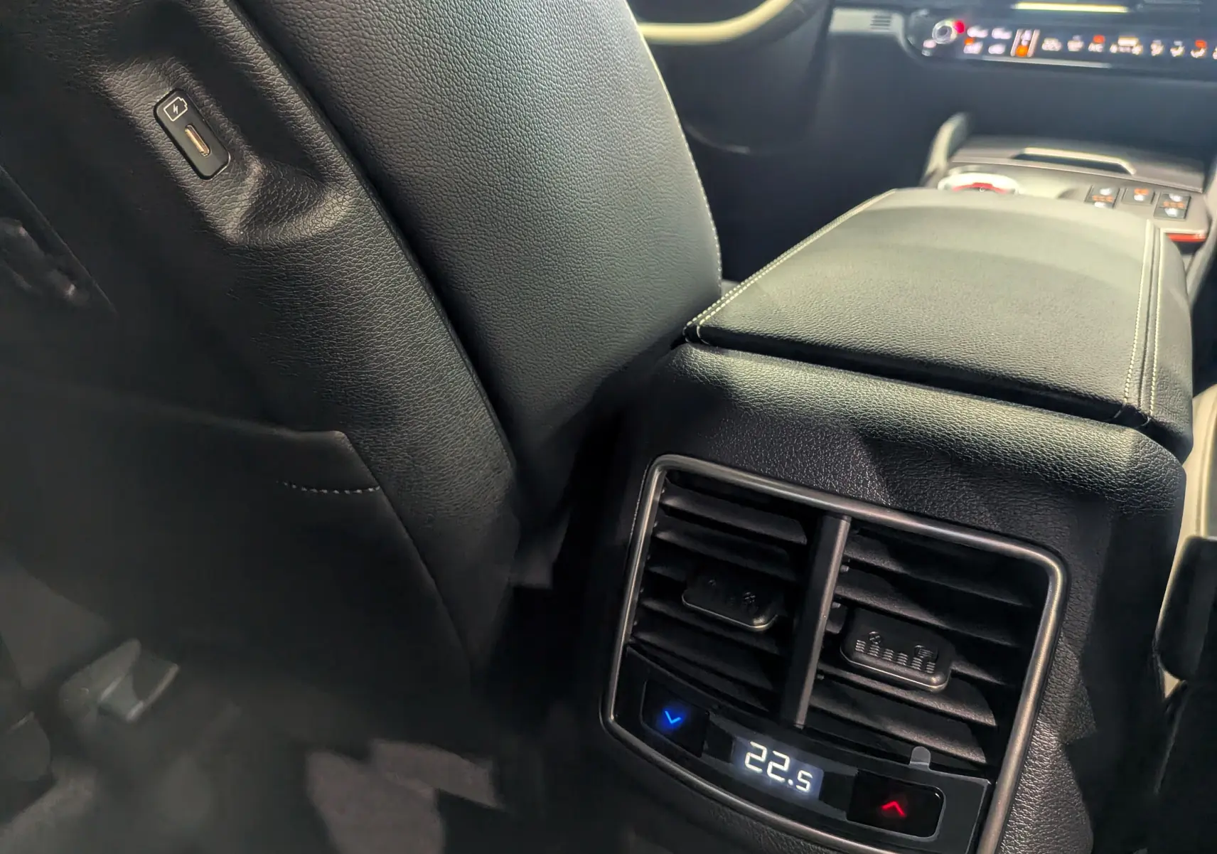 Gros plan sur la console centrale arrière noire du Kia Sportage 2025 avec réglage numérique de la climatisation à 22,5°C.