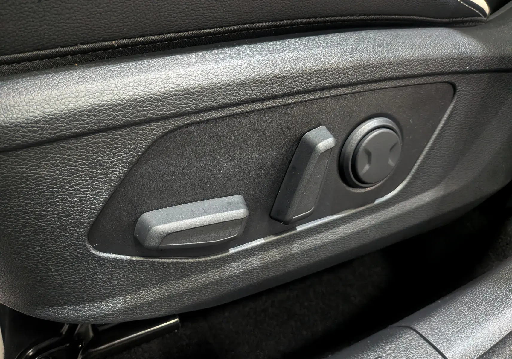 Gros plan sur les commandes de réglage électrique du siège conducteur du Kia Sportage gris céramique 2025.