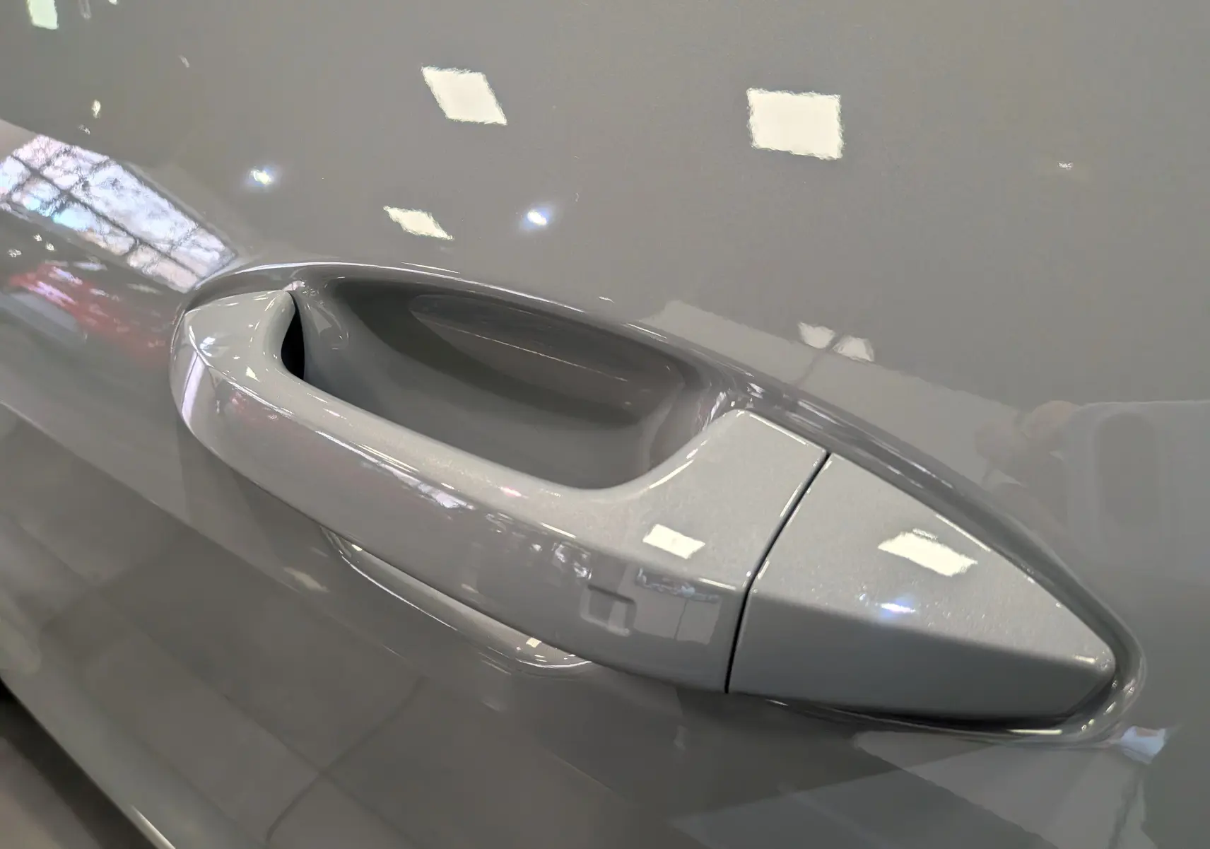 Poignée de porte gris céramique du KIA SPORTAGE 2025 vue en gros plan sur le côté gauche.