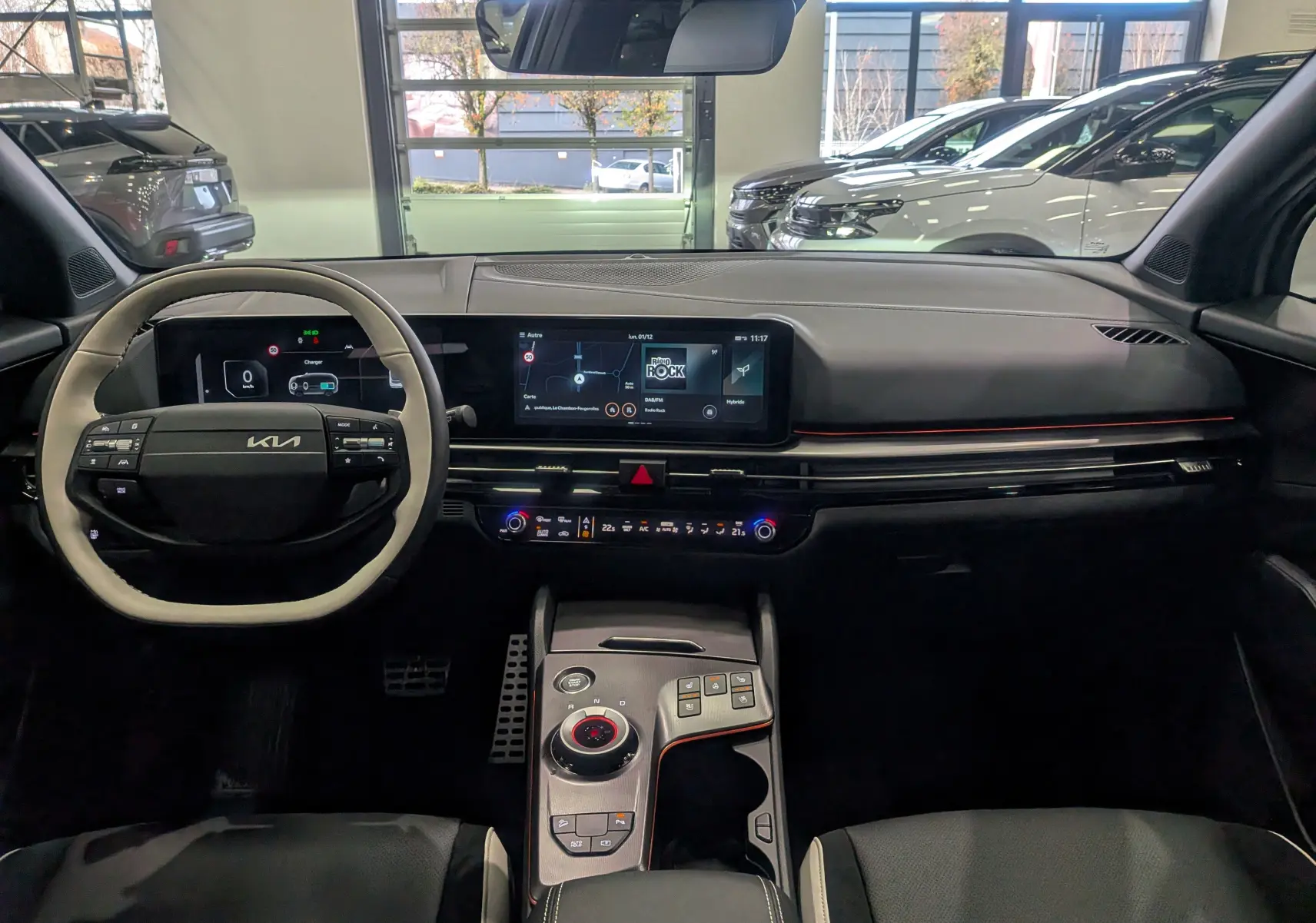 Intérieur du Kia Sportage 2025 GT Line hybride, tableau de bord moderne avec écran tactile et volant bi-ton noir et beige.