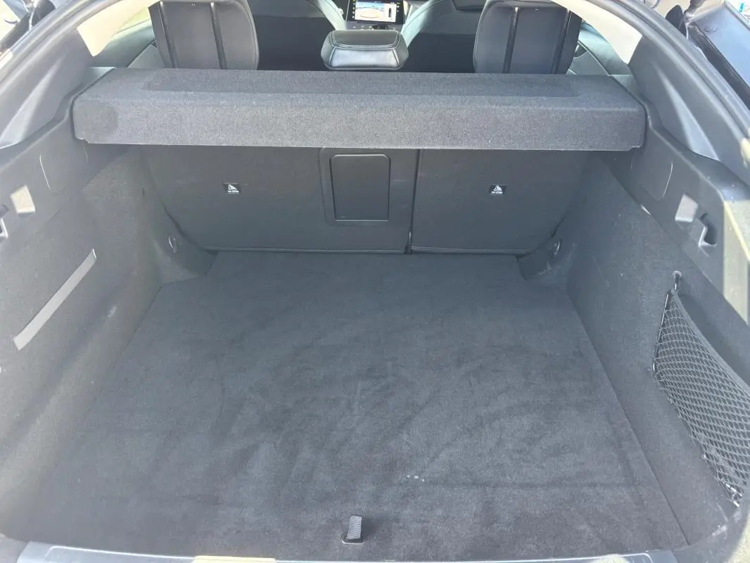 Coffre spacieux noir de la Peugeot 408 Hybrid 136 e-DCS6 Allure vu de l'arrière avec cache-bagages en place.