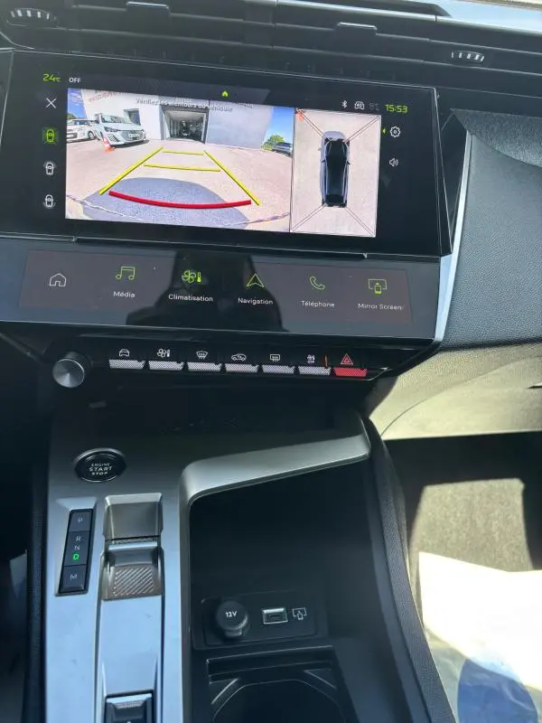 Vue intérieure du tableau de bord de la Peugeot 408 Hybrid 136 e-DCS6 Allure 2025, écran tactile avec caméra de recul et console centrale noire.