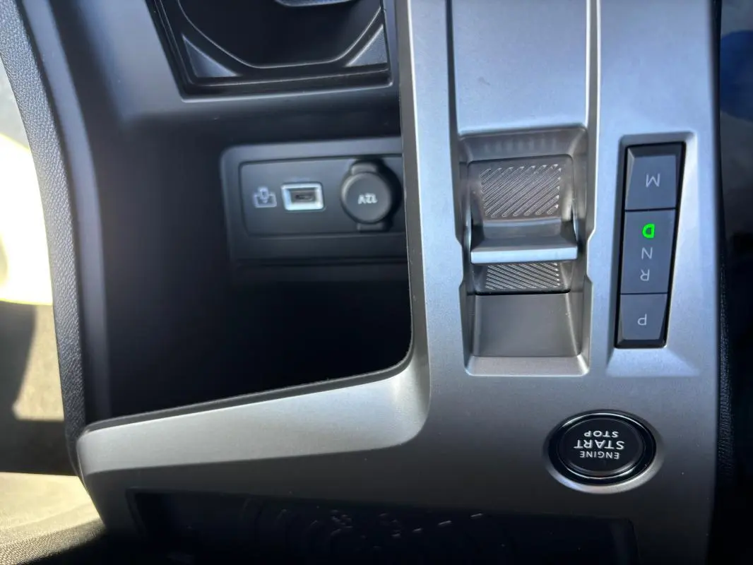 Gros plan sur la console centrale grise du Peugeot 408 Hybrid noir, montrant levier de vitesses électronique et bouton start/stop.