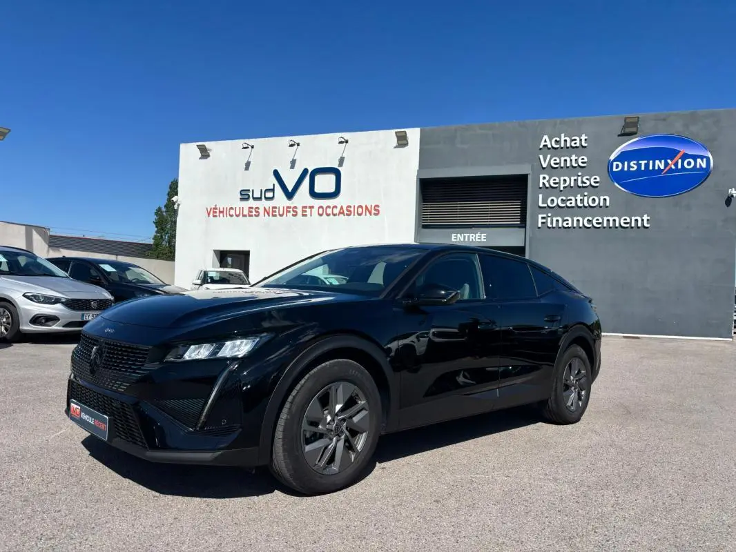 Peugeot 408 Hybrid noir vue 3/4 avant droit, jantes alliage 19 pouces, stationnée devant un concessionnaire.