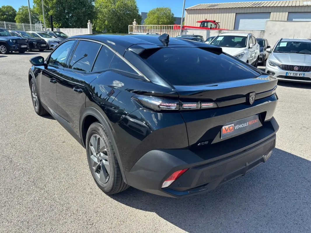 Vue 3/4 arrière droite d'une Peugeot 408 Hybrid noire, avec jantes alliage 19 pouces et vitres teintées.