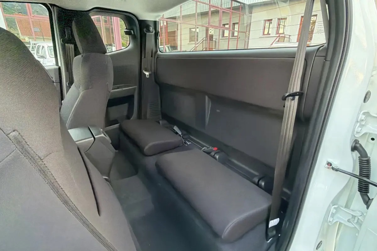 Vue intérieure côté droit du pick-up Isuzu D-MAX 2026 Splash White, montrant les sièges arrière rabattus en tissu noir.