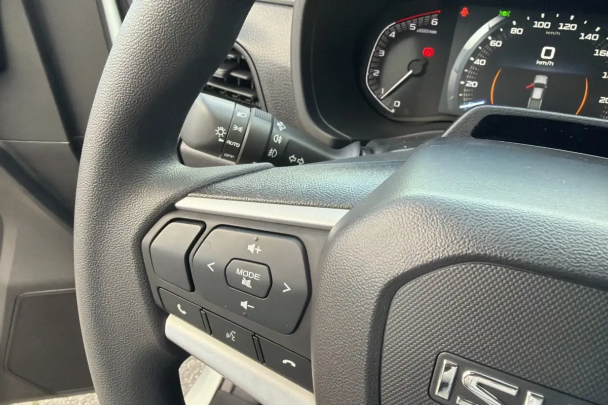 Gros plan sur le volant multifonctions noir de l’Isuzu D-MAX 2026 avec commandes audio et tableau de bord digital.