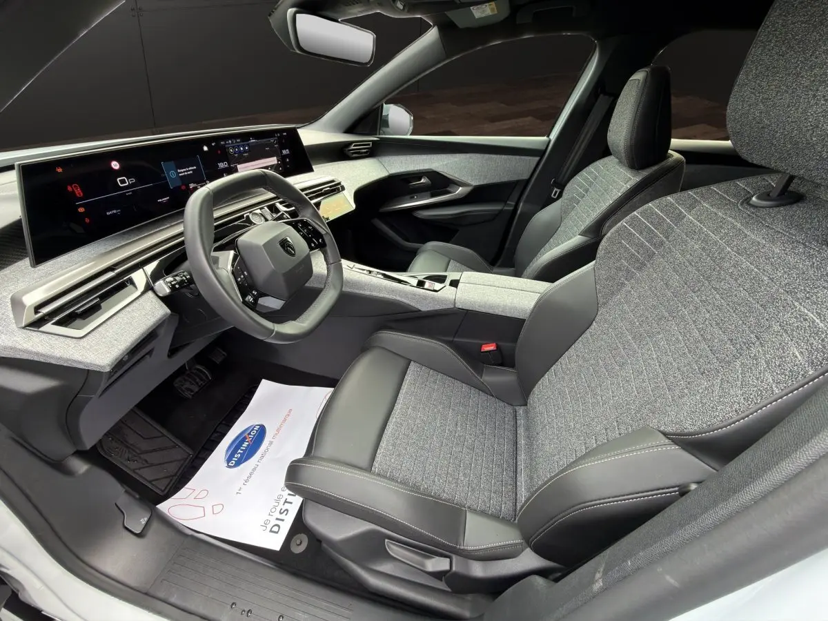 Vue intérieure côté conducteur du Peugeot 3008 2025, montrant les sièges gris et noir, le volant cuir multifonctions et l'écran tactile panoramique.