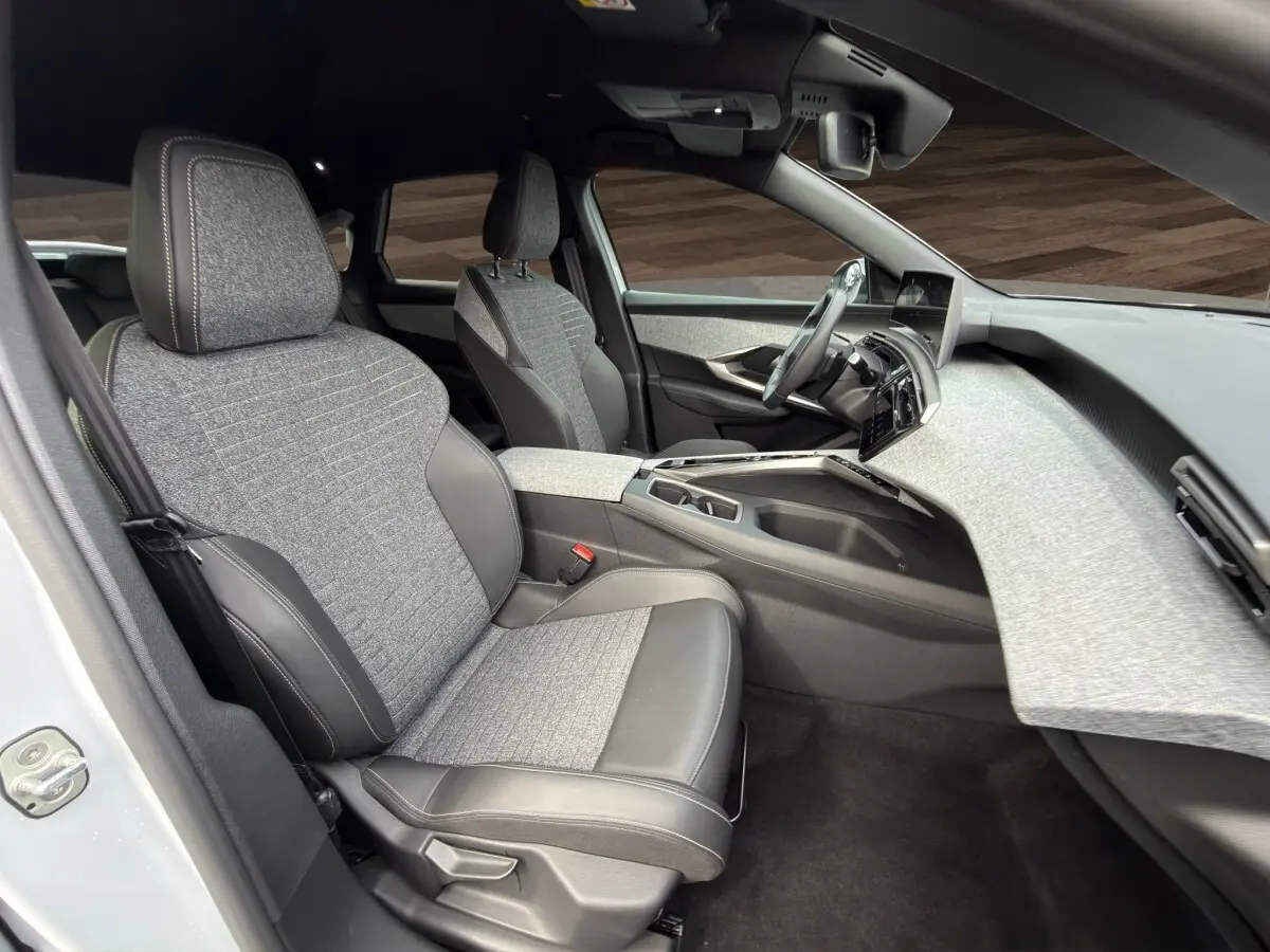 Intérieur avant droit du Peugeot 3008 blanc 2025, sièges tissu et cuir gris, tableau de bord clair moderne.