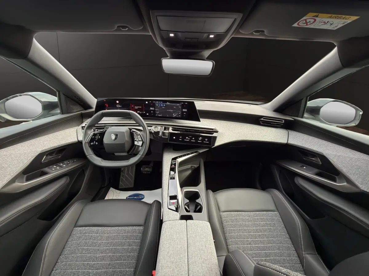 Vue intérieure avant du Peugeot 3008 blanc 2025, volant cuir multifonctions et tableau de bord numérique panoramique.