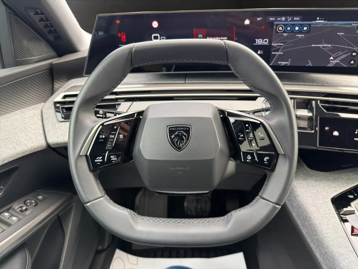 Vue rapprochée du volant cuir multifonctions du Peugeot 3008 blanc 2025 avec tableau de bord numérique panoramique.