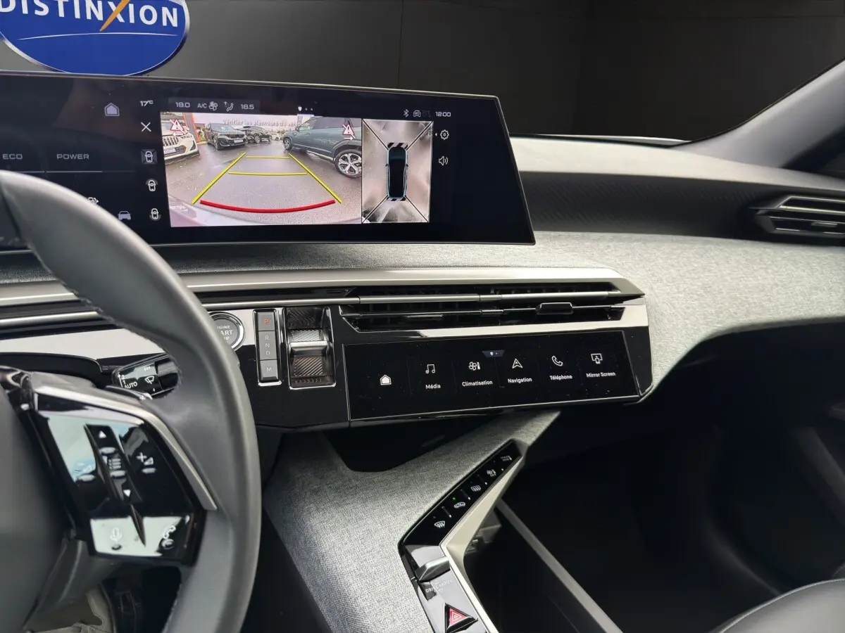 Vue intérieure du tableau de bord du Peugeot 3008 blanc, avec écran tactile affichant la caméra de recul et commandes modernes.