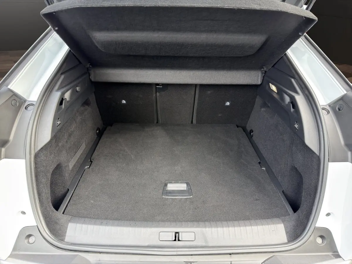 Coffre ouvert vu de l'arrière d'un Peugeot 3008 blanc, espace de chargement propre et spacieux avec cache-bagages relevé.