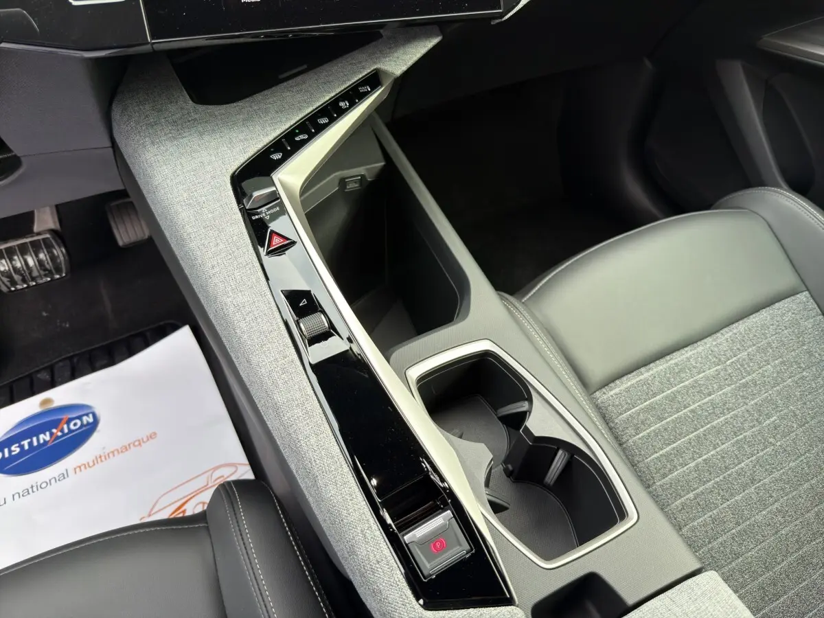 Vue rapprochée de la console centrale grise et noire du Peugeot 3008 blanc, avec porte-gobelets et commandes tactiles.