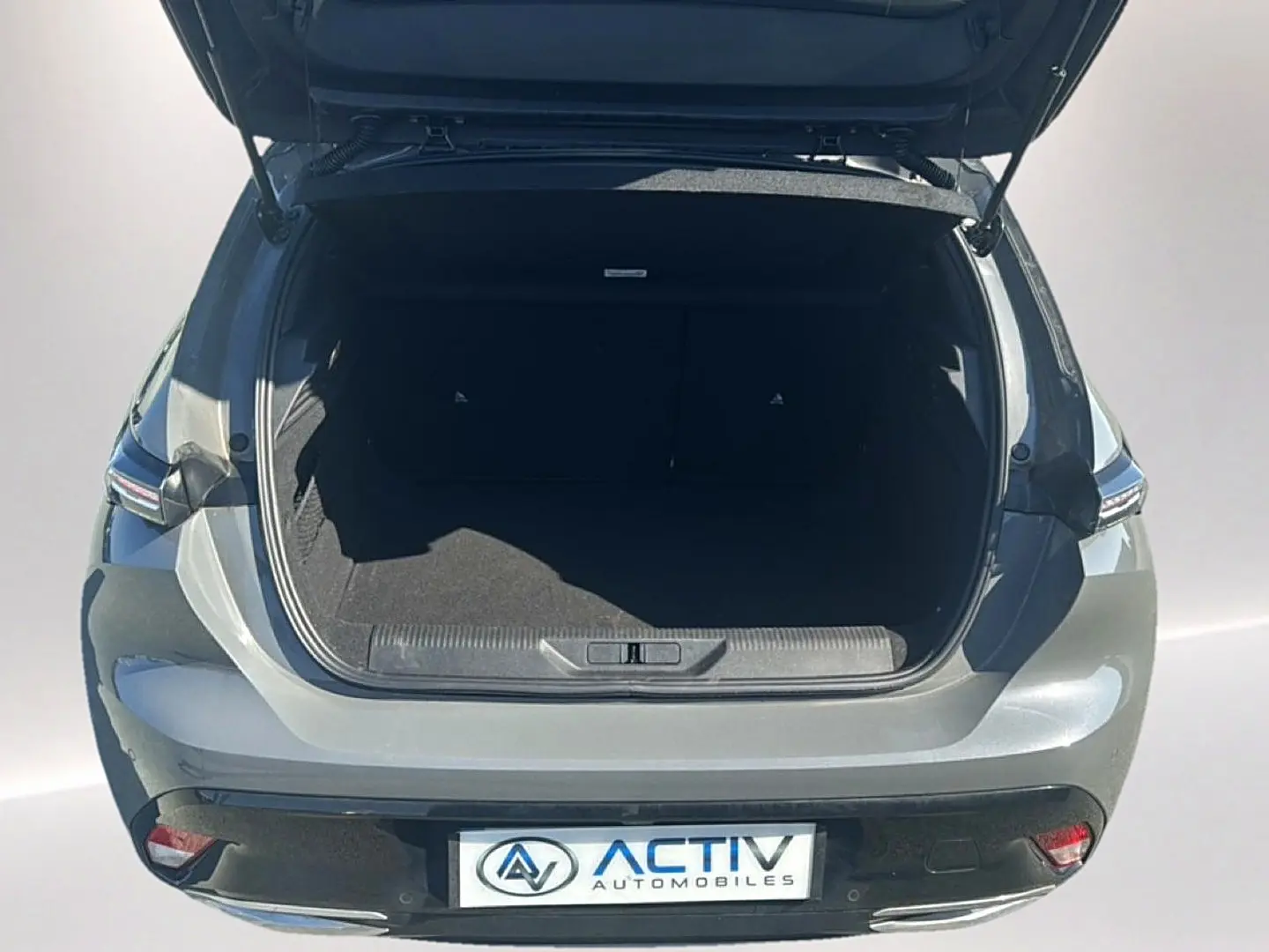 Vue arrière ouverte d'un Peugeot 308 gris 2025, coffre spacieux et feux arrière LED visibles.