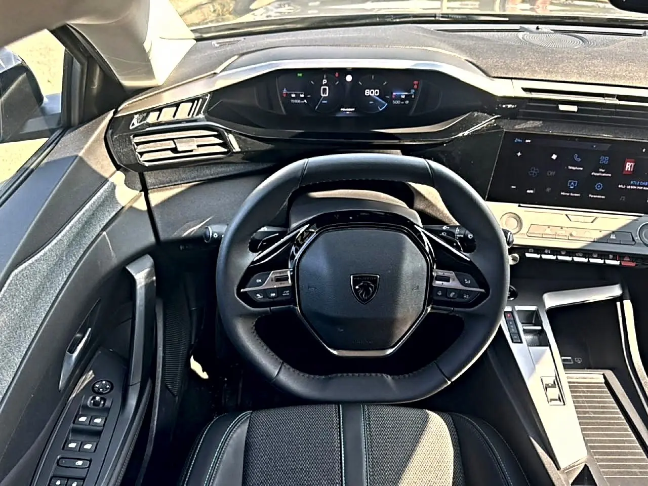 Vue intérieure centrée sur le volant multifonction et le tableau de bord numérique de la Peugeot 308 gris 2025.