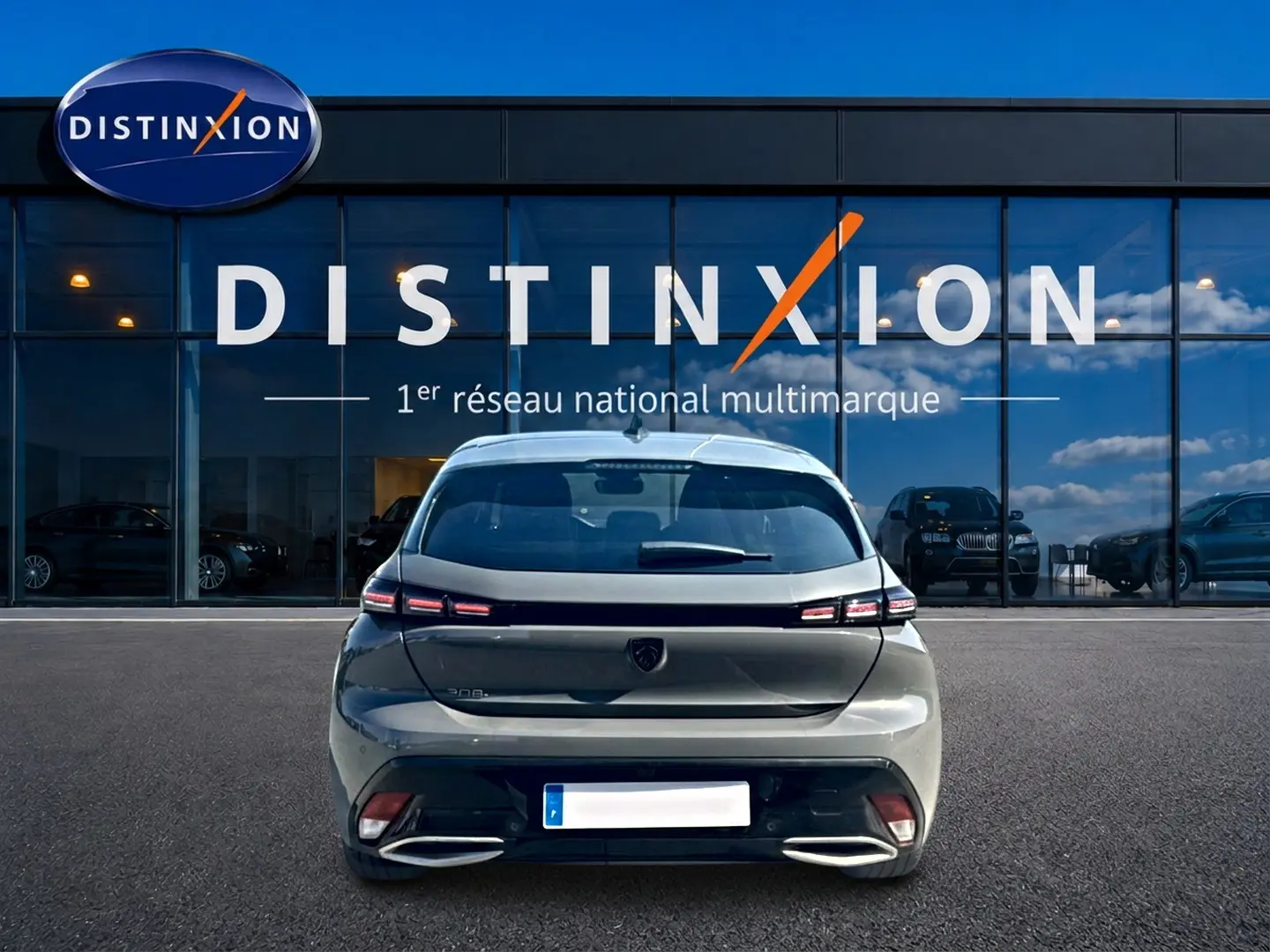 Vue arrière d'une Peugeot 308 gris métallisé garée devant une vitrine avec logo Distinxion.
