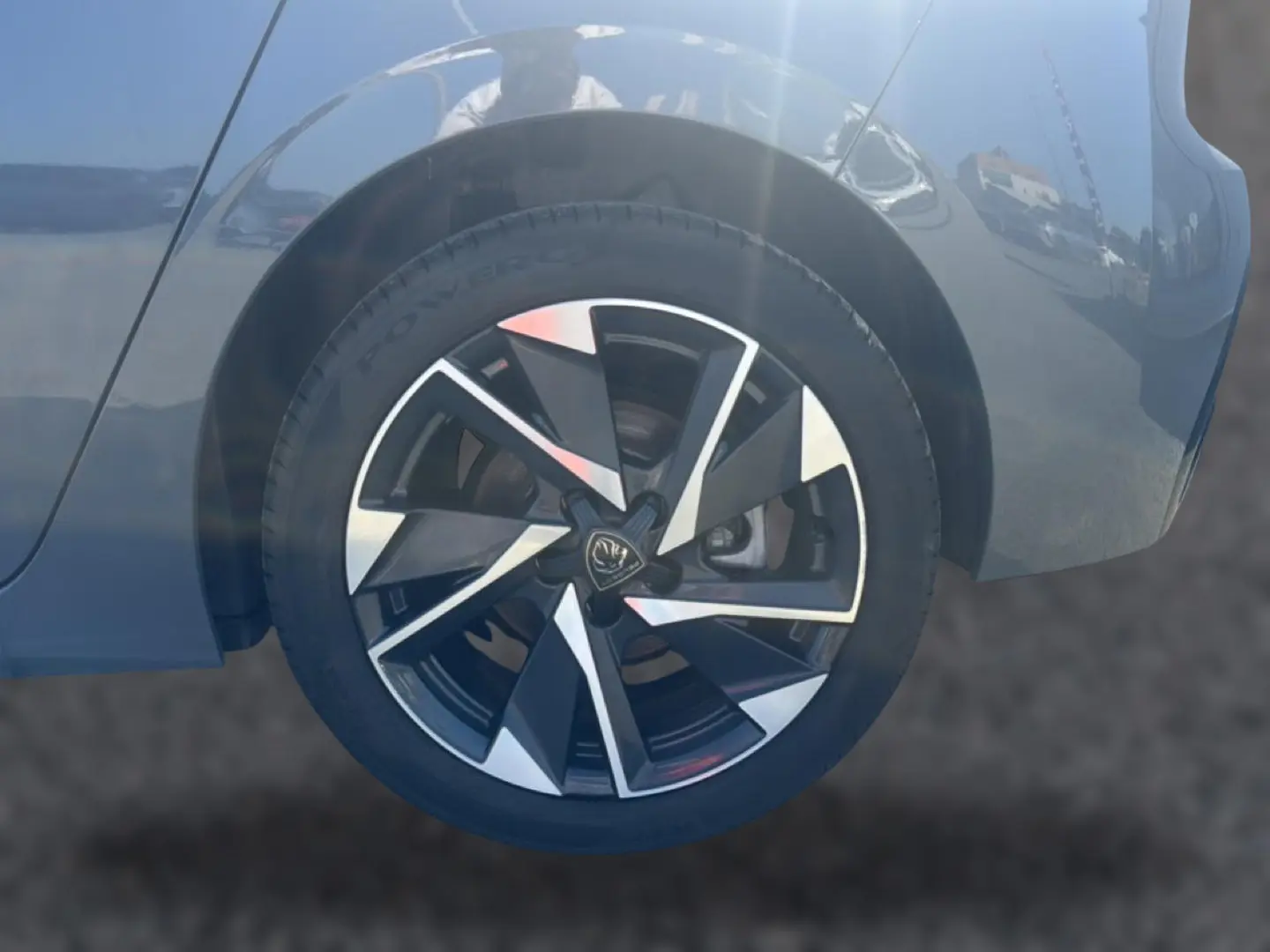 Gros plan sur la roue avant droite d'une Peugeot 308 gris métallisé avec jante alliage au design moderne.