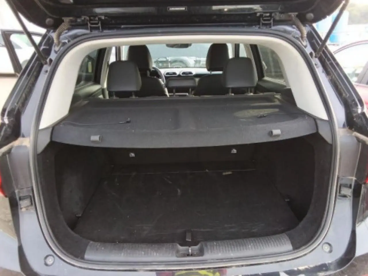 Vue arrière du coffre ouvert du MG MOTOR ZS 1.5 Hybrid+ 197 Luxury noir, avec cache-bagages en place.