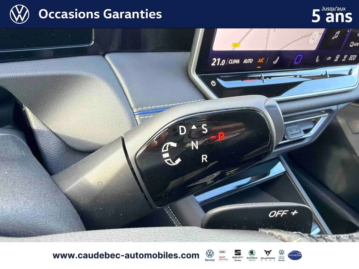 Gros plan sur la commande de boîte manuelle noire dans l’habitacle du Volkswagen Tiguan argent Dolomite, avec écran tactile en arrière-plan.