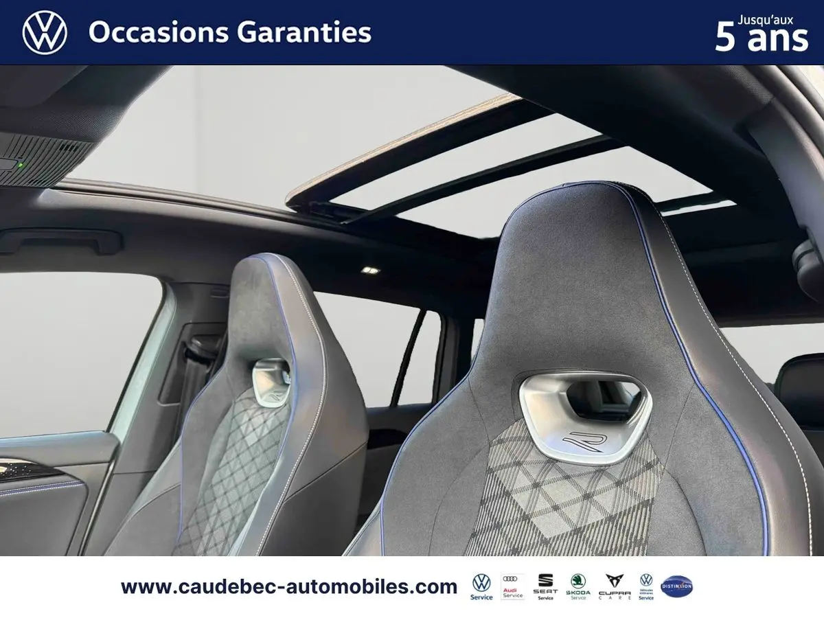 Intérieur du Volkswagen Tiguan eHybrid 2025, vue sur sièges sport R gris avec surpiqûres bleues et toit ouvrant panoramique.