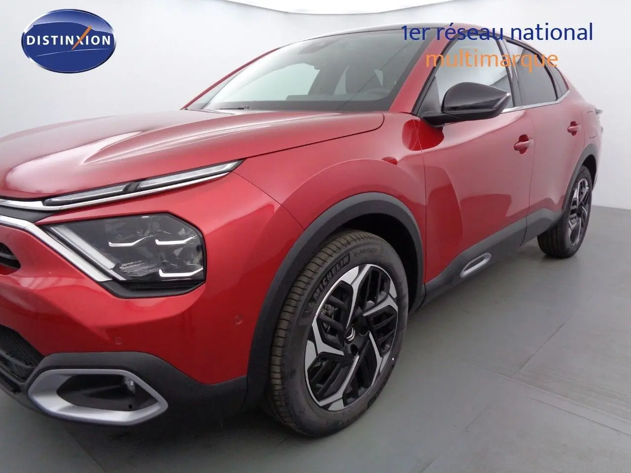 Vue 3/4 avant droit d'une Citroën C4 X rouge Elixir Métal avec jantes alliage bicolores et détails noirs contrastants.