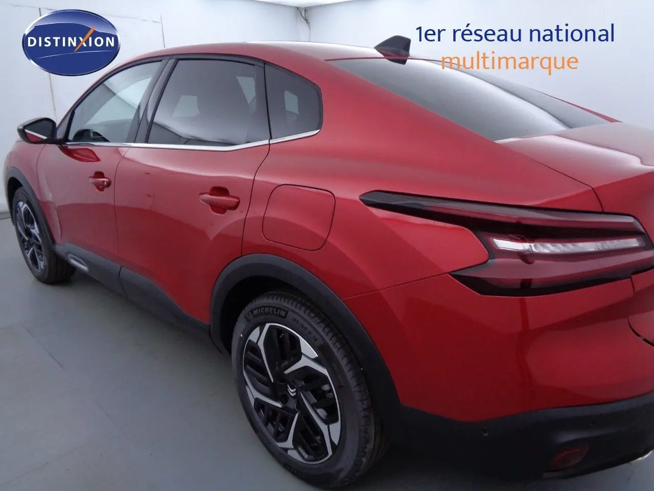 Vue 3/4 arrière droite d'une Citroën C4 X rouge Elixir Métal avec feux arrière LED et jantes bicolores.