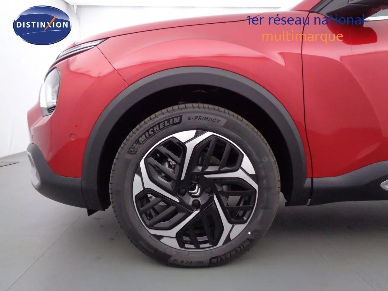 Gros plan sur la roue avant droite d'une Citroën C4 X rouge Elixir Métal avec jante noire et argentée design moderne.