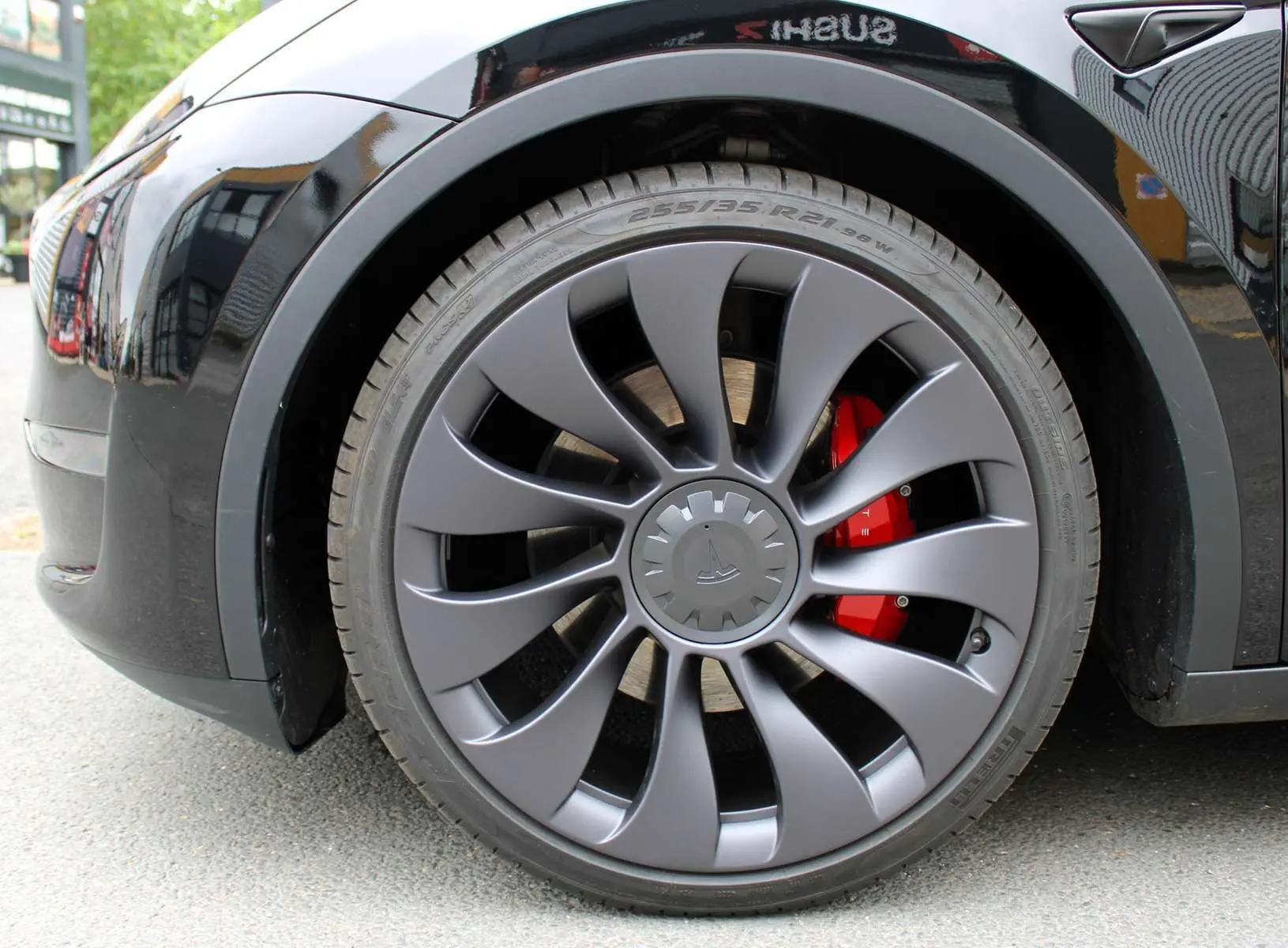 Gros plan sur la roue avant gauche noire métal d'une Tesla Model Y 2024 avec étrier de frein rouge visible.