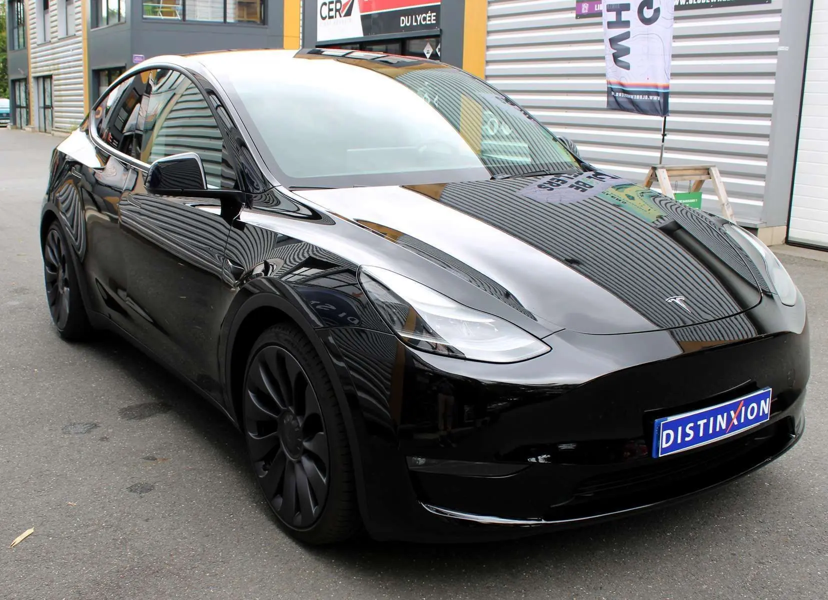 Tesla Model Y noir métal en vue 3/4 avant gauche, avec jantes noires et calandre lisse distinctive électrique.