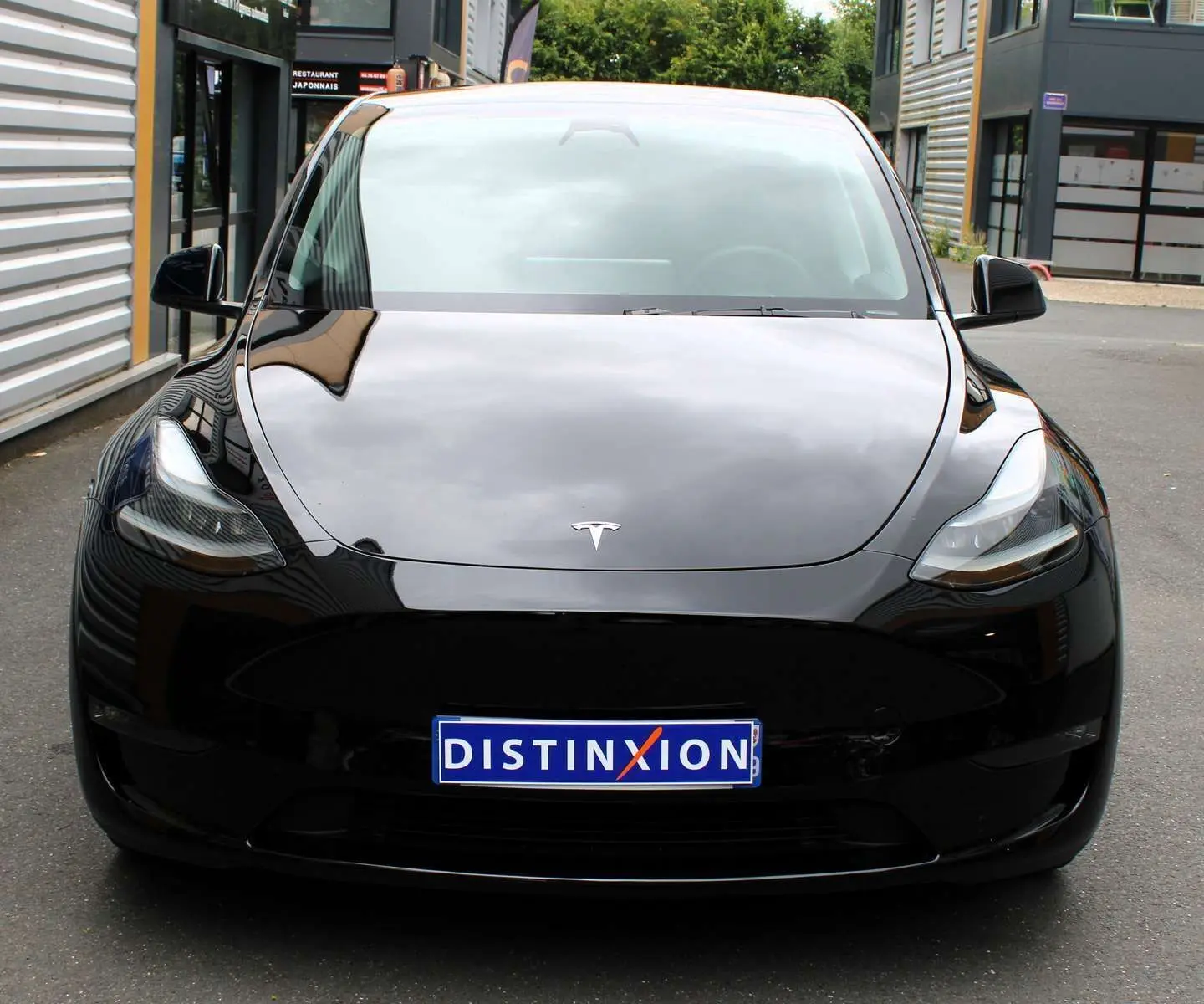 Vue frontale d'une Tesla Model Y noire métal 2024 avec logo distinctif et plaque d'immatriculation Distinxion.