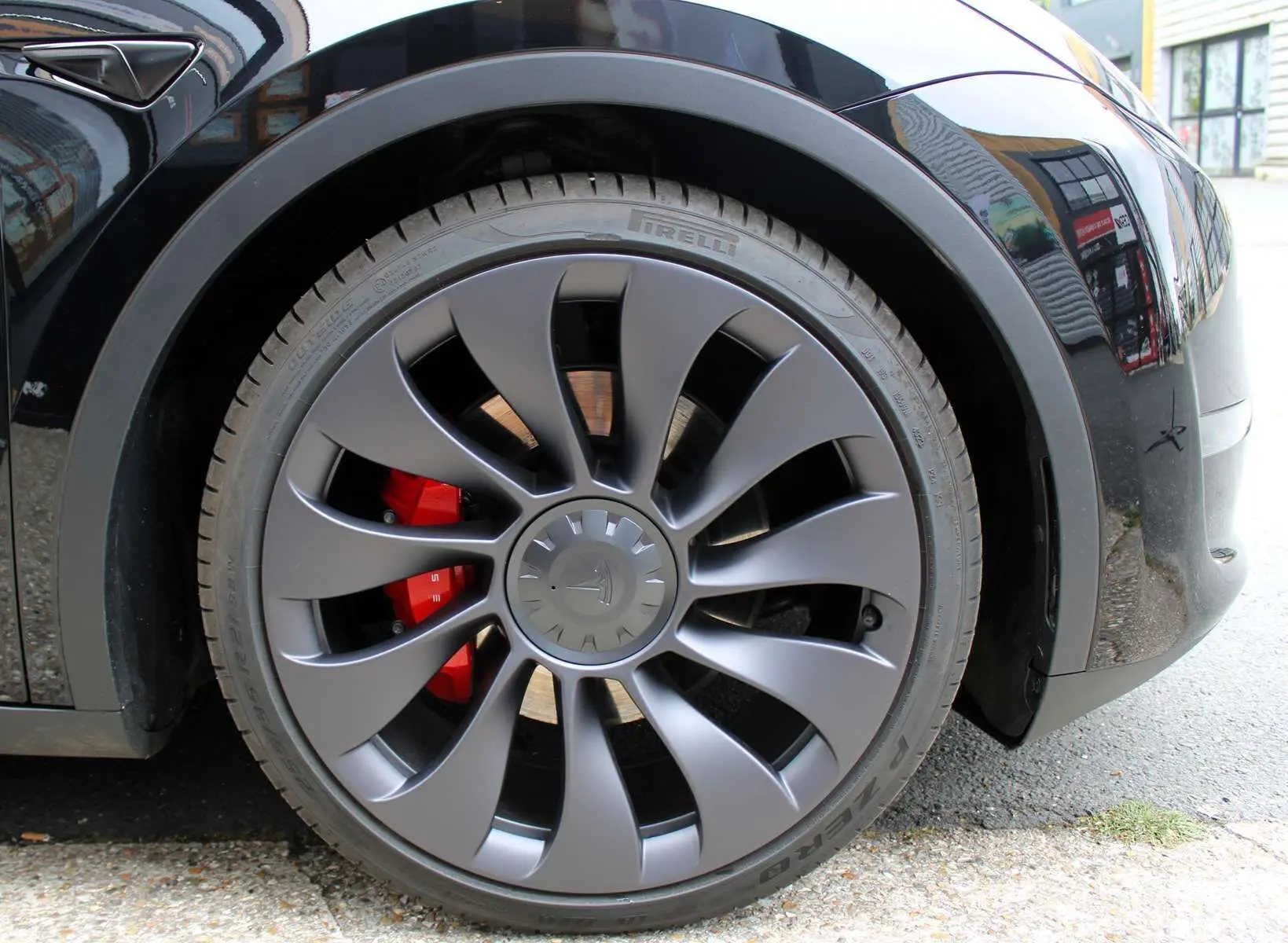 Gros plan sur la roue avant droite noire métallisée d'une Tesla Model Y 2024 avec étrier de frein rouge visible.