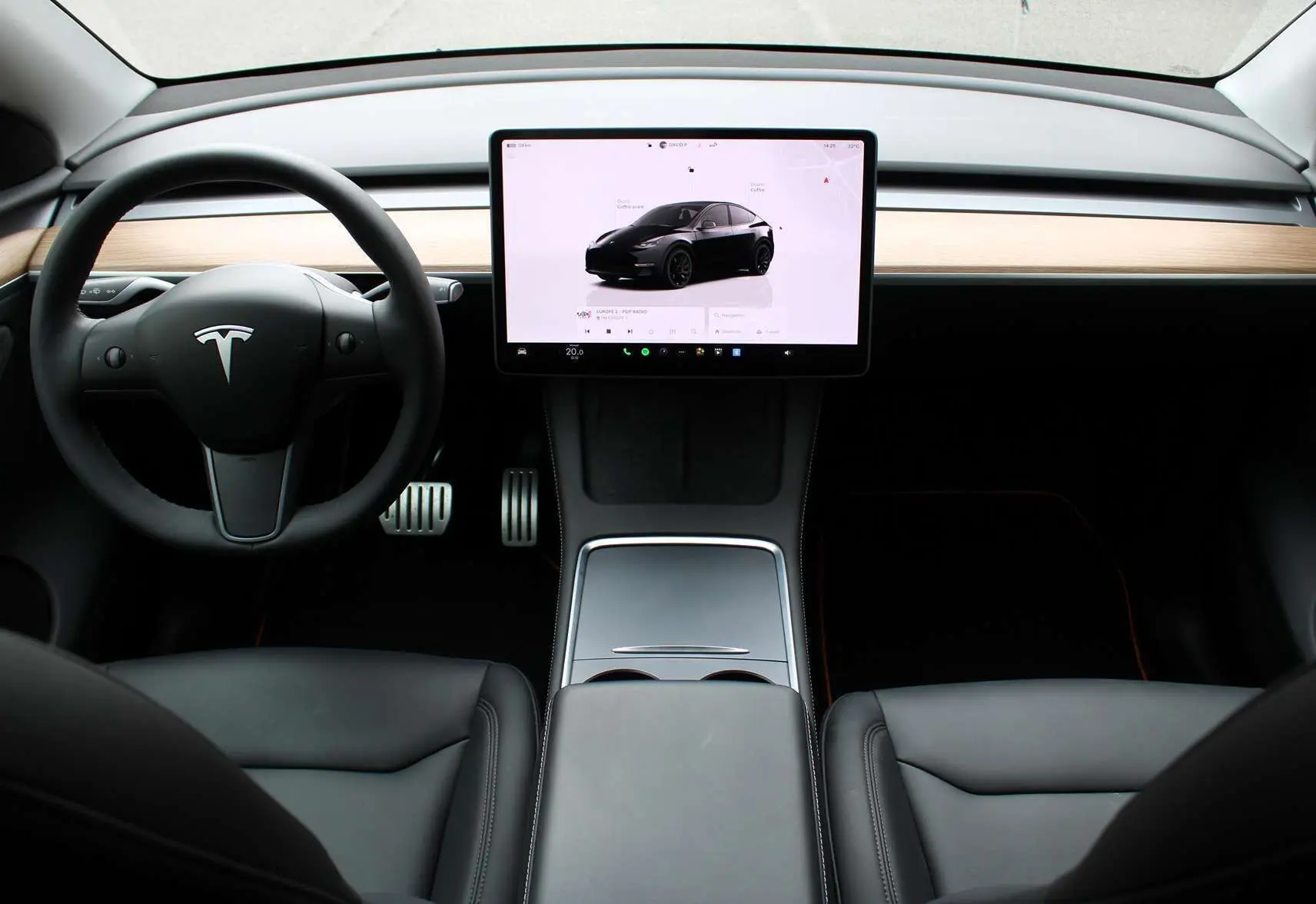 Intérieur avant de la Tesla Model Y Performance 2024 noir métal, tableau de bord minimaliste avec grand écran tactile central.