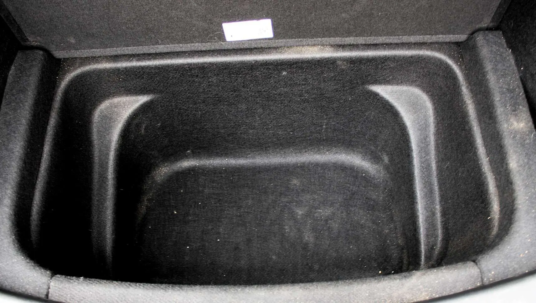 Coffre avant vide en tissu noir du Tesla Model Y Performance 2024, vue plongeante sur l'espace de rangement électrique.