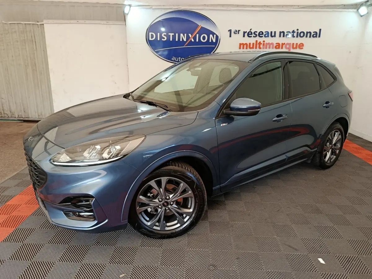 Ford Kuga bleu en vue 3/4 avant droit, avec jantes alliage et toit noir dans un showroom intérieur.
