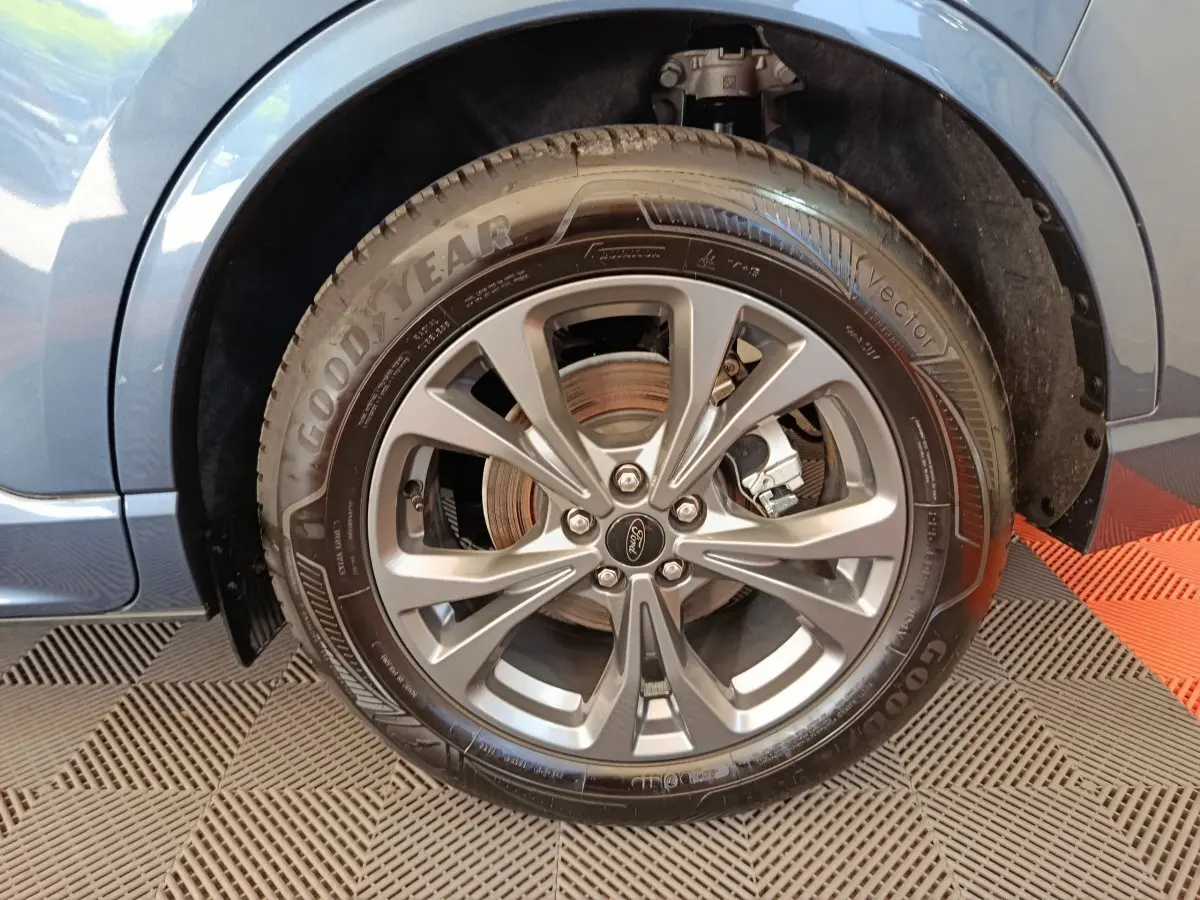 Gros plan sur la roue avant droite du Ford Kuga bleu 2024, mettant en valeur la jante alliage et le pneu Goodyear.