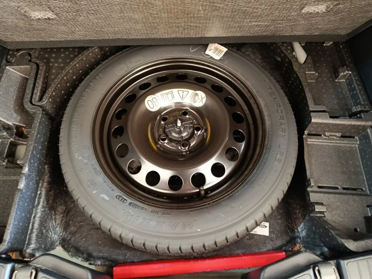 Vue plongeante sur la roue de secours noire logée dans le coffre du Ford Kuga bleu 2024 St Line.
