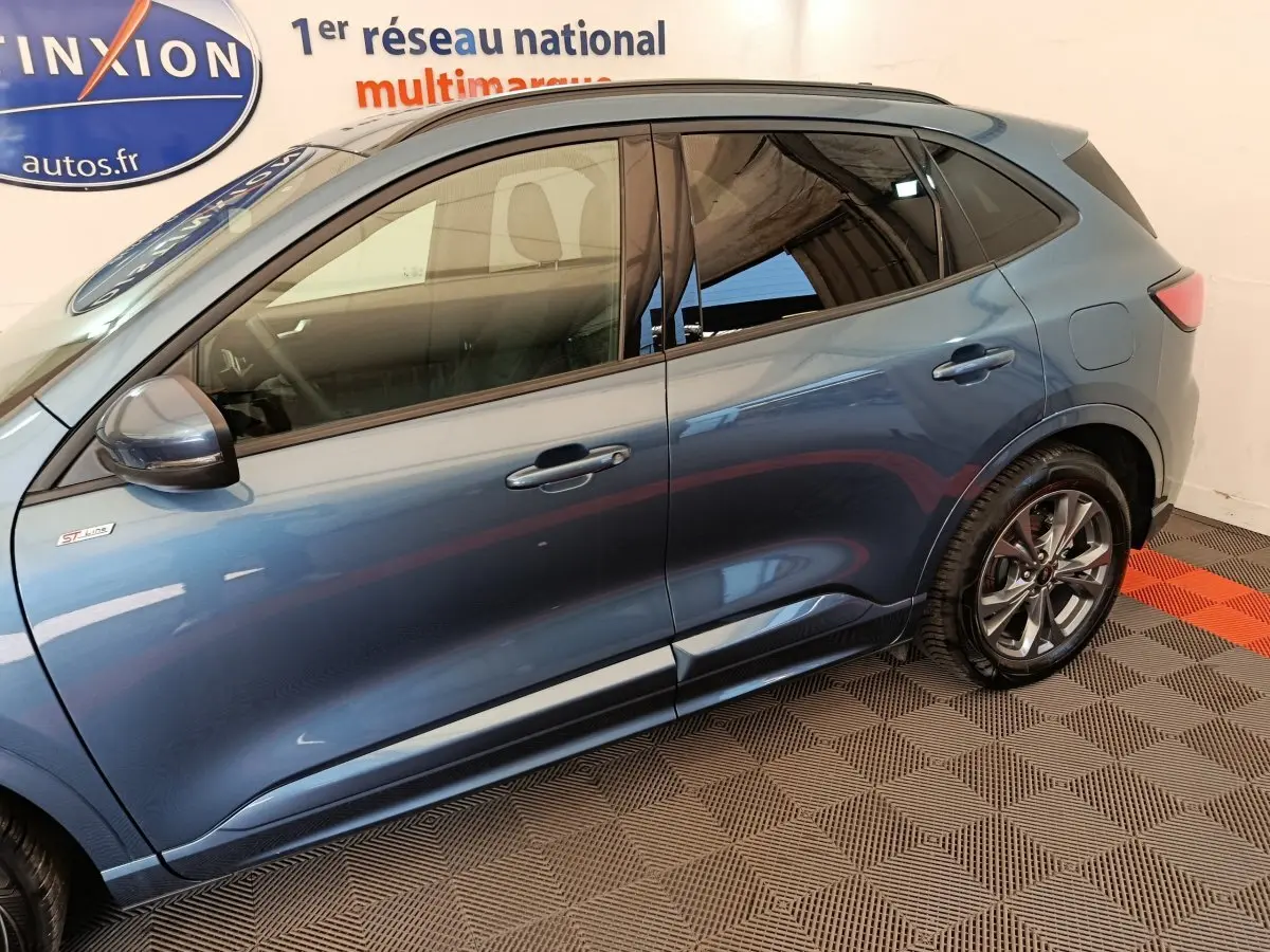 Profil côté gauche du Ford Kuga 2024 bleu, finition St Line avec jantes alliage et rétroviseurs assortis.